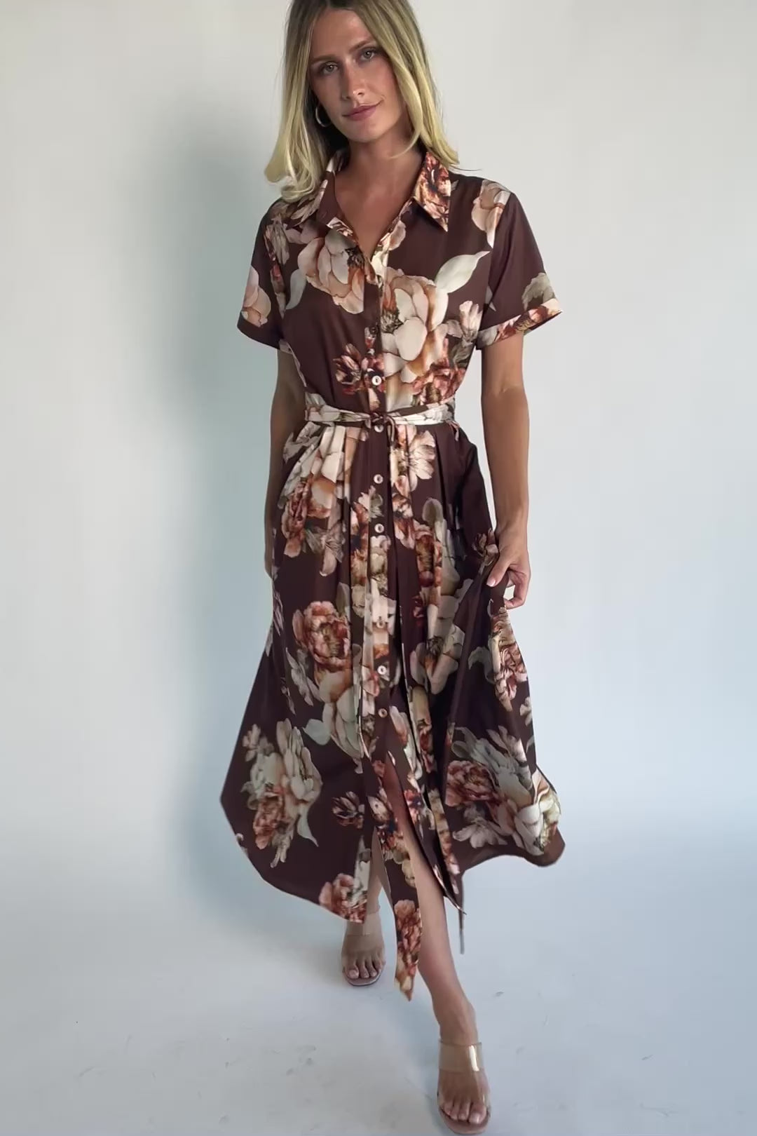Model wearing the Blythe Midi Dress in Brown Floral featuring a collared neckline, functional button-front bodice, short rolled sleeves, and a removable waist tie.