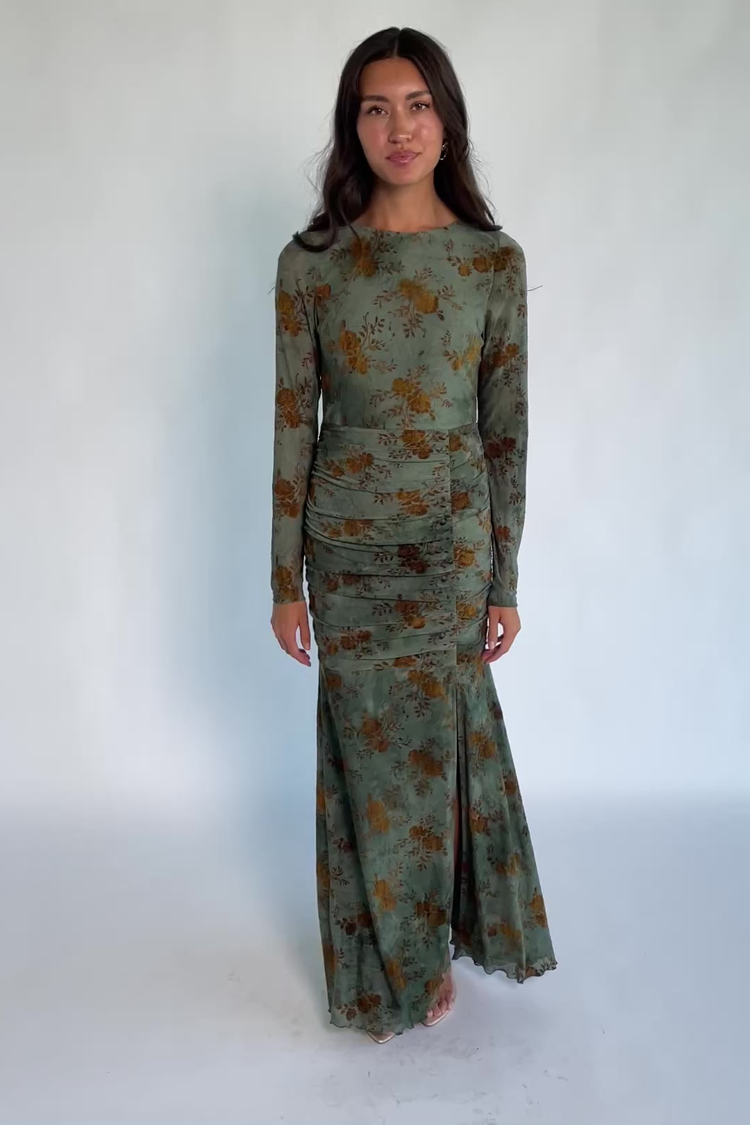 Model wearing a green mesh maxi dress with copper velvet burnout detailing, a high round neckline, and long sheer sleeves.
