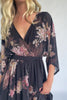 Model wearing a black floral maxi dress with a surplice V-neckline, kimono sleeves, and an elastic waist with a removable sash tie.