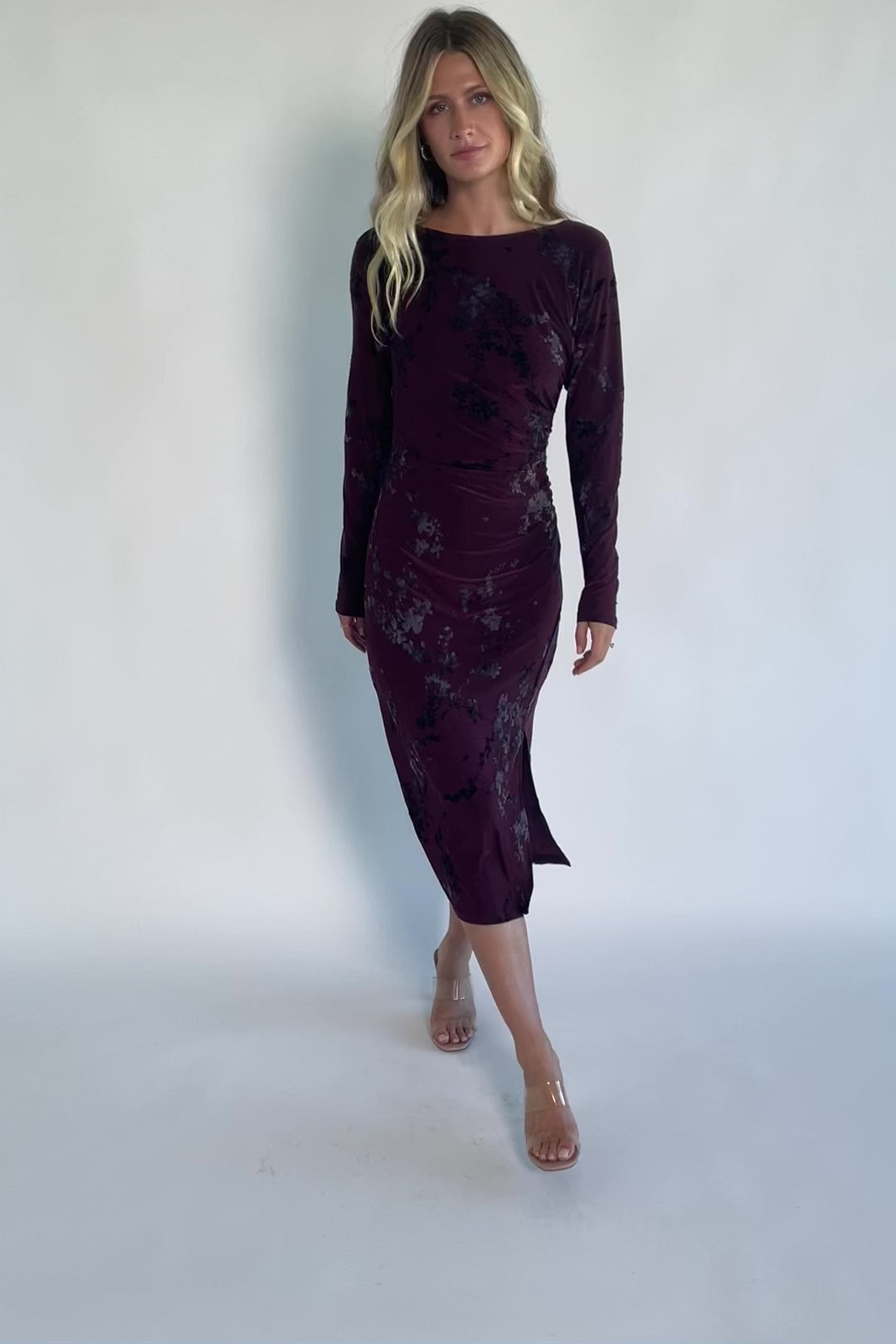 Model wearing a dark plum velvet floral midi dress with a boat neckline, long sleeves, and a fitted silhouette.