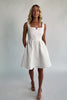 Model wearing an ivory sleeveless mini dress with a square neckline and subtle notch detail.
