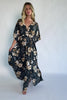 Model wearing a dark jade floral maxi dress with a surplice V-neckline, kimono sleeves, and an elastic waist with a removable sash tie.