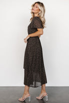 Back view of Prim Pleated Midi Dress showing button-and-keyhole closure and the gentle pleat flow of the midi skirt in black floral print.