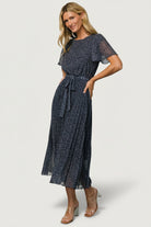 Close-up of navy leaf print and chiffon texture on Prim Pleated Midi Dress, highlighting pleating detail and subtle taupe tones.