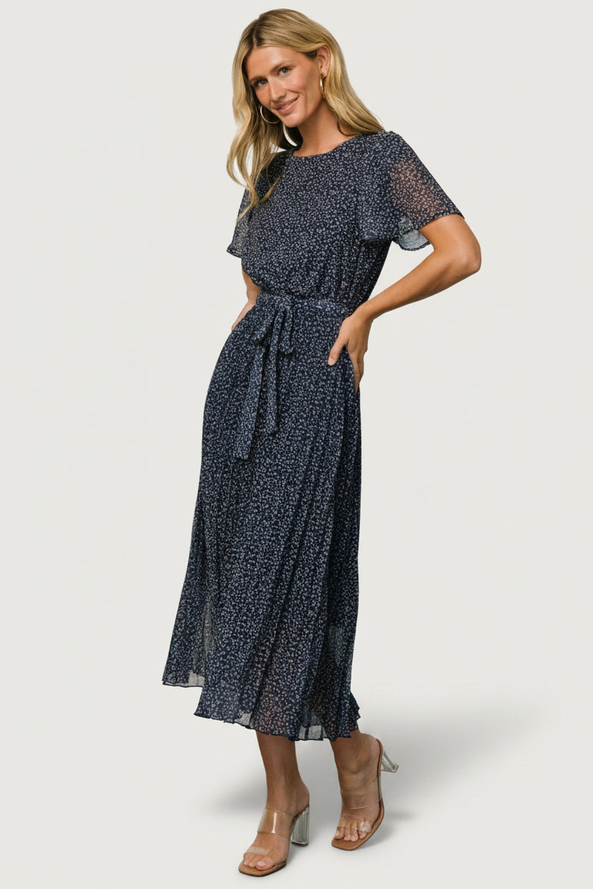 Close-up of navy leaf print and chiffon texture on Prim Pleated Midi Dress, highlighting pleating detail and subtle taupe tones.