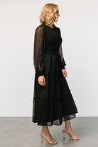 Studio shot of Remi ribbed maxi dress in black laid flat showing tiered skirt silhouette and sweater-knit bodice texture.