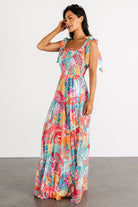 Full-length styling image showing Santana maxi dress in motion; tiered hem, smocked top, and vibrant multi floral print for vacation wear.