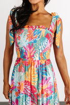 Side profile of Santana maxi dress showing tiered skirt movement and flowing silhouette in bright multi floral print on model.