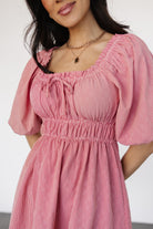 Model wearing the Shawna short dress in red gingham, highlighting the double elastic waist, short sleeves with elastic shoulders, and hidden side pockets.