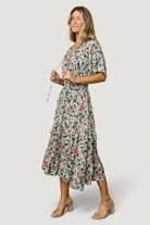 Back view of the Spell Boho Midi Dress in sage and pink floral, highlighting the smocked waist and skirt drape on a model.