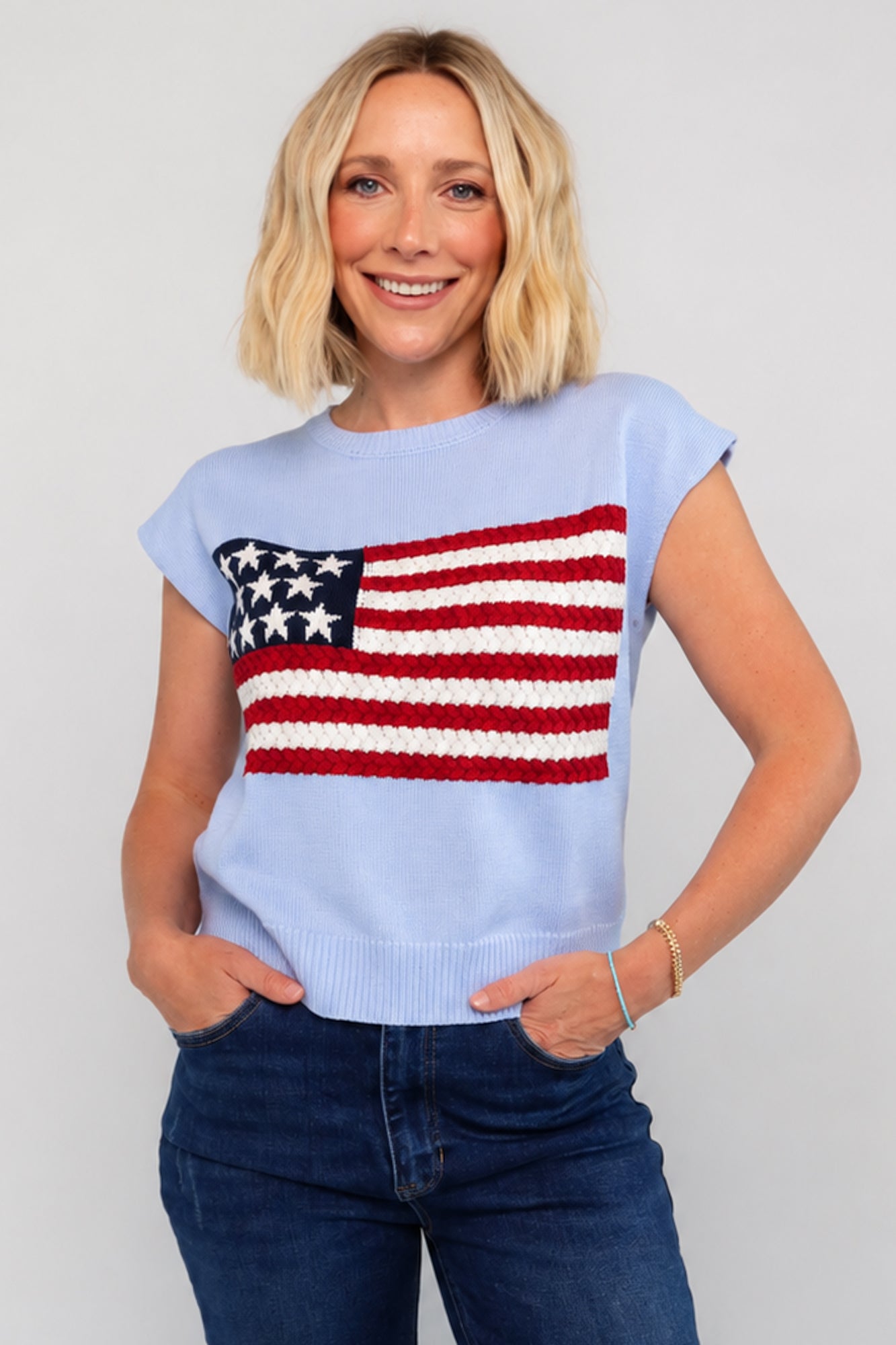 Model wearing a sleeveless knit with flag sweater top.