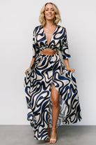 Three-quarter side view showing kimono-style sleeves, cut-out front bodice detail, elasticated waist and left leg slit on a flowing satin skirt.