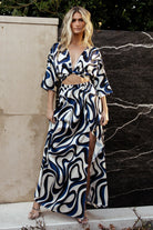 Front view of ivory maxi dress with navy and blue multi-print, V-neckline, adjustable tie, and flowing unlined skirt for warm-weather wear.