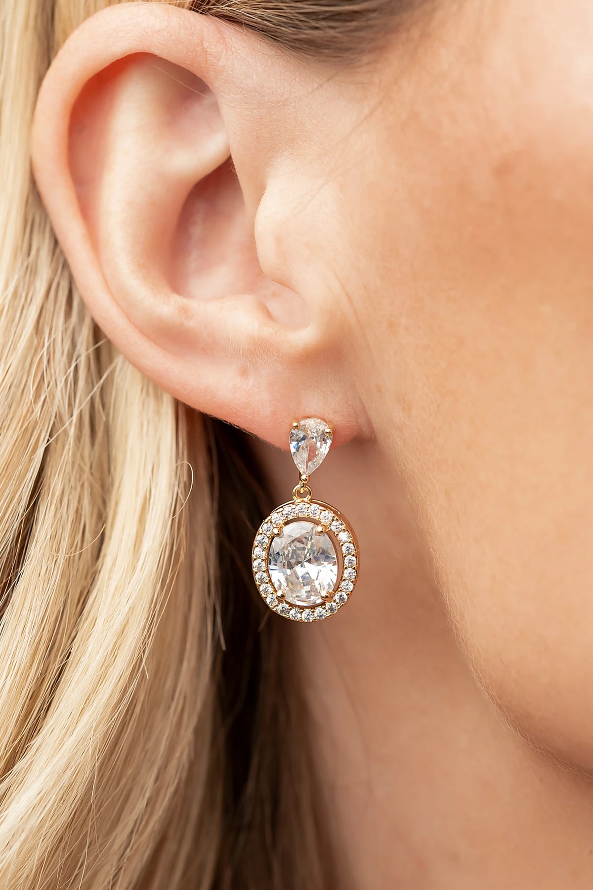 Stena Oval Dangle Drop Earrings in Gold with oval center stone and pavé stone border.
