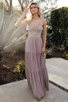 Front model view of dusty mauve maxi dress with lace bodice, adjustable double criss-cross straps, smocked back, and flowing tiered skirt, fully lined.