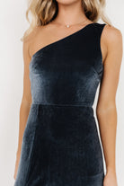 Side view of Tatiana velvet one-shoulder maxi in slate blue highlighting the asymmetrical neckline and mid-thigh slit for movement.