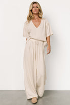 Close-up of top fabric and center detail on natural linen-blend two-piece showing texture and V-neckline with short sleeves.