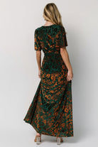 Full-length image of Uma Velvet Maxi Dress in bronze and jade styled with a detached sash to emphasize waist definition and flowing skirt.