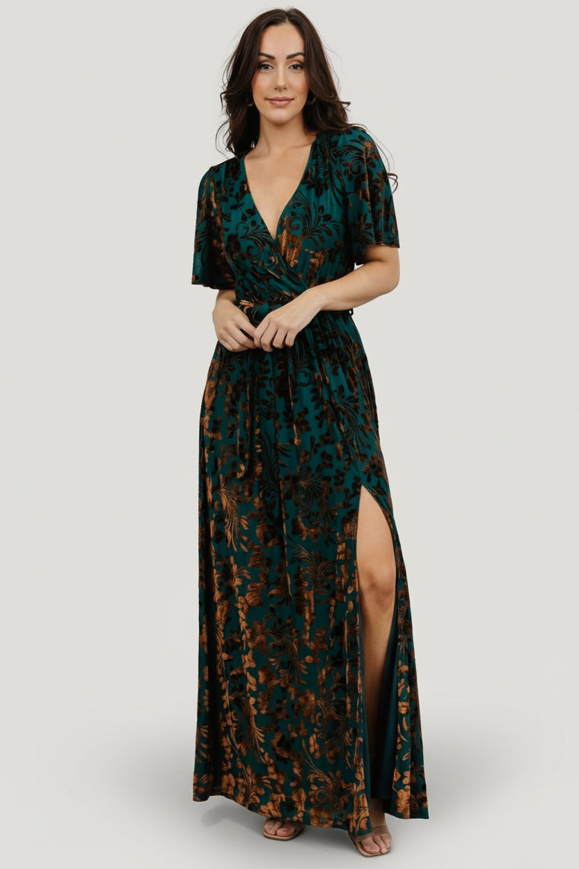 Editorial-style image of Uma Velvet Maxi Dress in bronze and jade highlighting full skirt movement, floral burnout detail, and maxi length.
