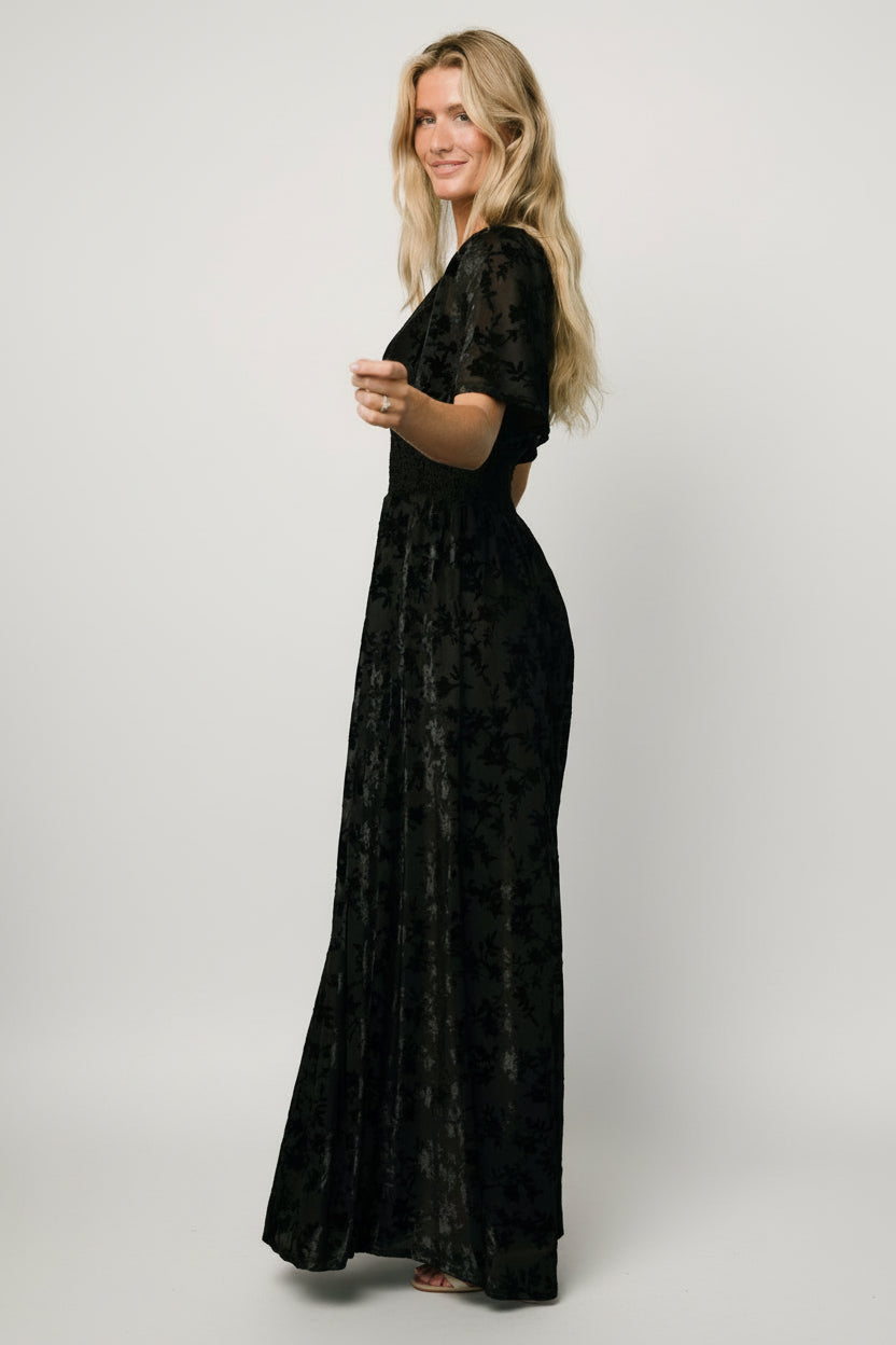 Three-quarter view of black Veronica Velvet Maxi Dress highlighting embossed velvet texture, smocked waist and gentle skirt drape.