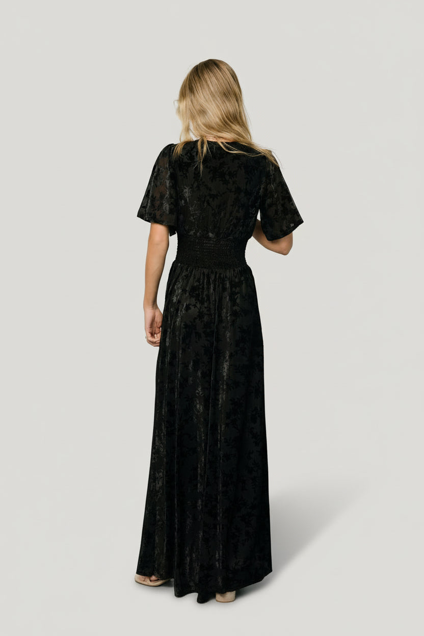 Model wearing Veronica Velvet Maxi Dress in black, styled with minimal jewelry to highlight the textured velvet and elegant silhouette.