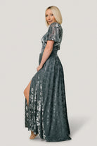 Model wearing Veronica velvet maxi dress in slate blue showing deep V-neckline and short flowy sleeves with the embossed velvet close-up.