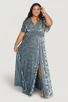Three-quarter view of Veronica velvet maxi in slate blue highlighting smocked waist, gentle drape of fabric, and movement at the skirt with embroidered texture.