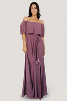 Front full-length view of off-shoulder vintage plum maxi dress on model, showing elastic neckline, flowing skirt, and left-side slit for movement and elegance.