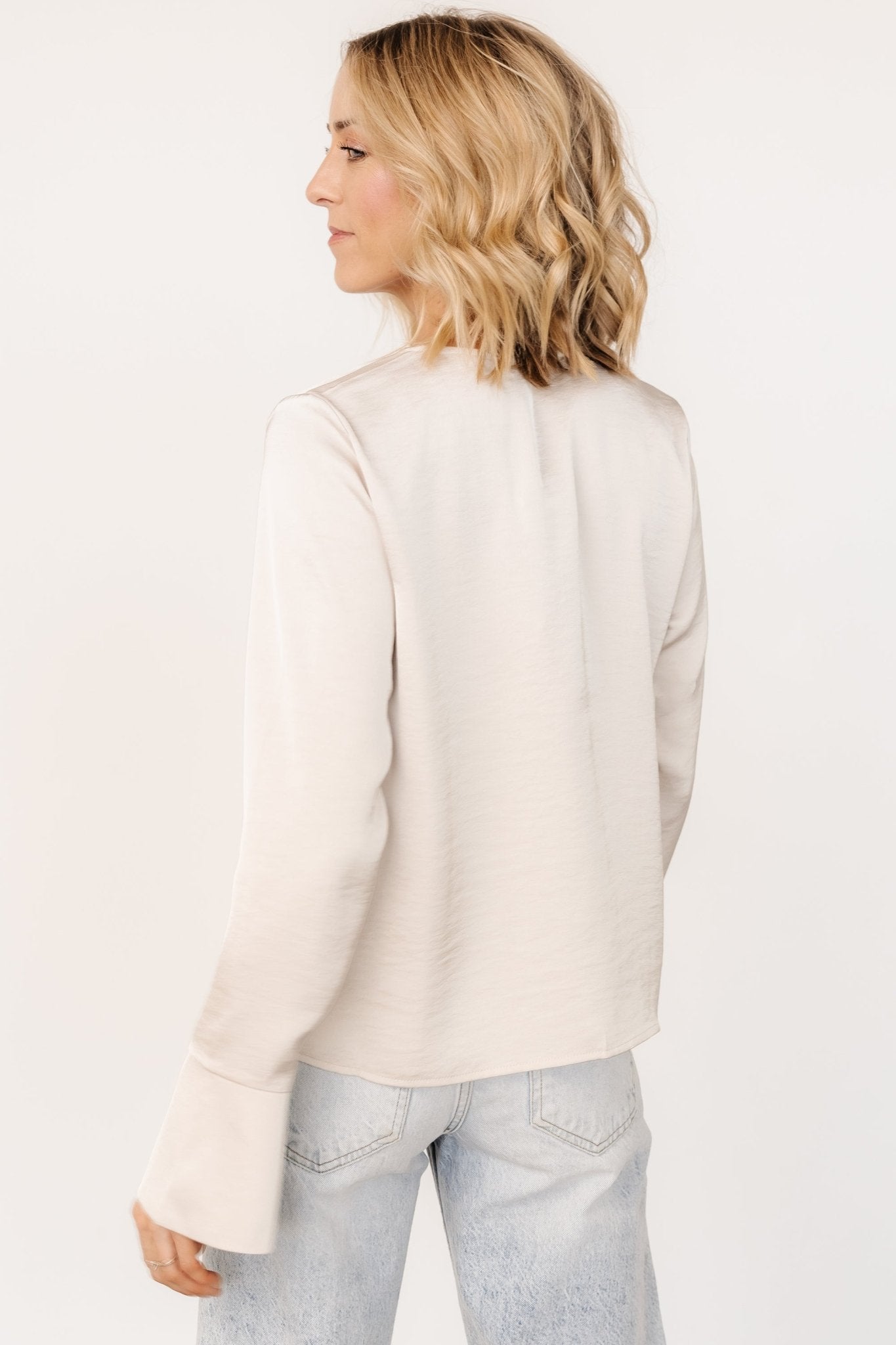 Close-up of satin-like fabric and pleating near the tie-neck, highlighting pearl champagne color and subtle texture.