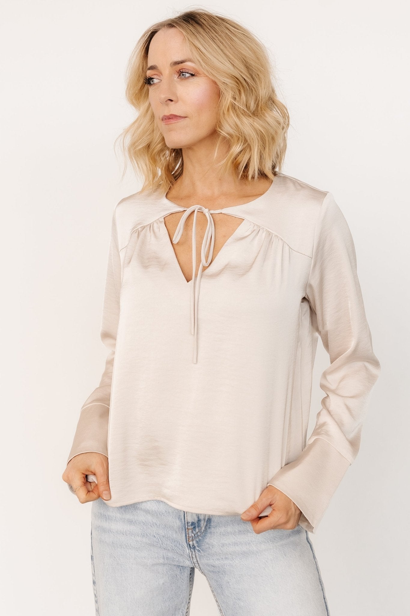 Styled outfit image: pearl champagne satin blouse paired with jeans, showcasing polished day-to-evening versatility and fit.