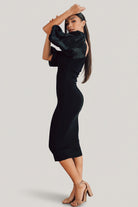 Side view of black bodycon midi dress on model, illustrating the curve-hugging fit and hem length that falls below the knee.