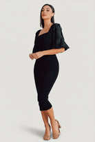 Styled flat-lay of the Weyland bodycon midi dress in black, emphasizing square neckline, embossed sleeve texture, and midi length.