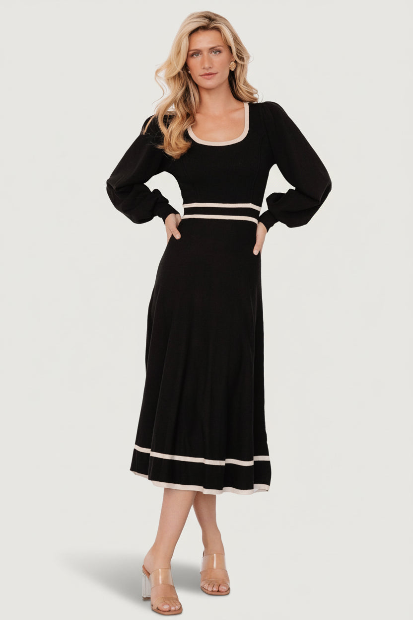 Front view of Winslet knit midi dress in black with cream piping, scoop neckline, gathered shoulders and A-line skirt on model.