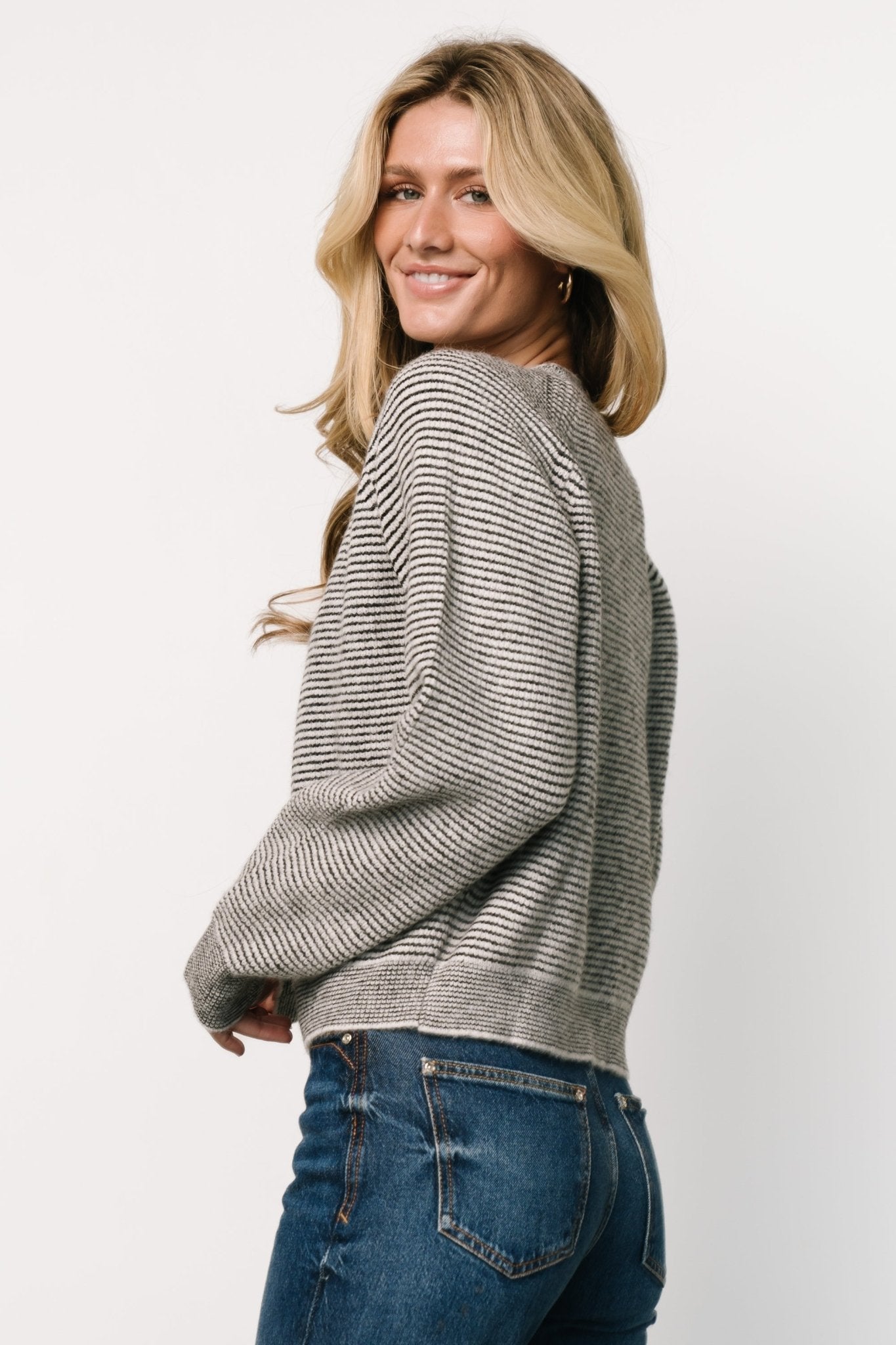Close-up of sleeve cuff and hem on the Zadie Striped Sweater in ivory and black displaying the contrast bands and stitch detail.