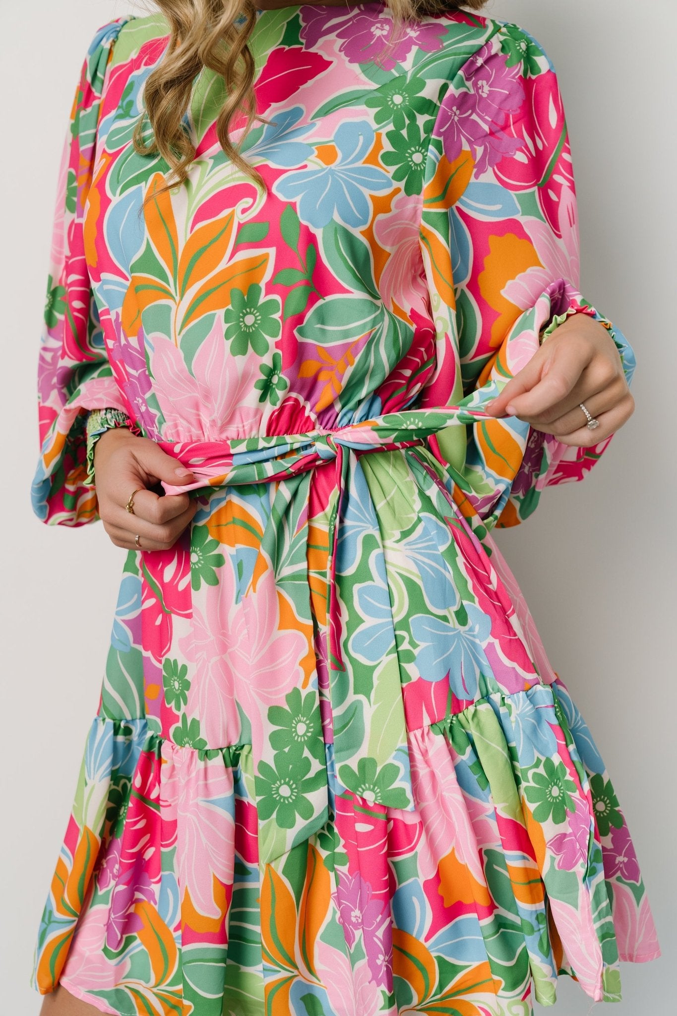 Flat-lay of the multi-color floral short dress showing overall silhouette, removable tie, elastic gathering at waist, and tiered hem.