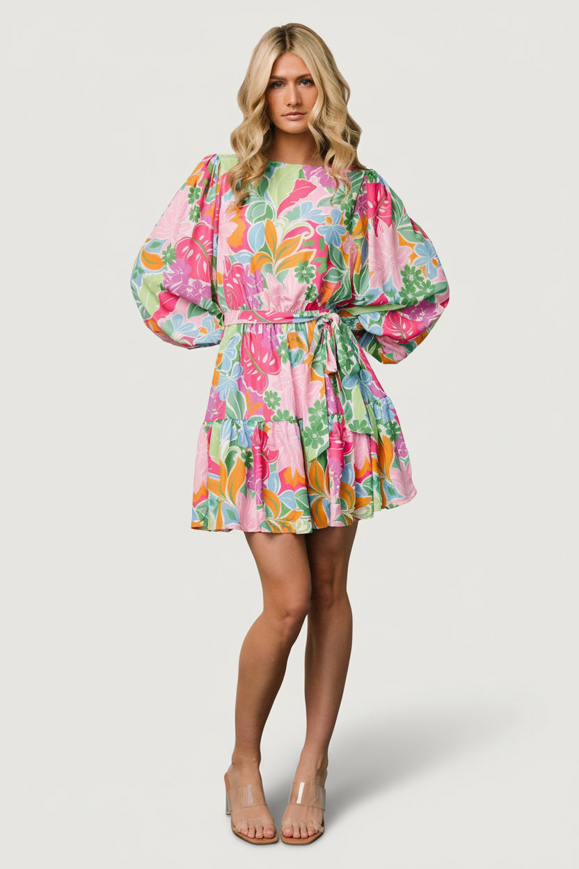 Front model view of multi-color floral short dress with lined body, sheer long sleeves, removable waist tie, and tiered ruffle hem.
