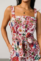 Flatlay of Zariah Romper showing full multi floral print, removable self-tie waist belt, and button-front details.