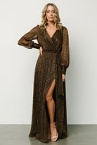 Front view of a model wearing a bronze sequin maxi gown with a faux-wrap surplice neckline and long sleeves, shown full length.