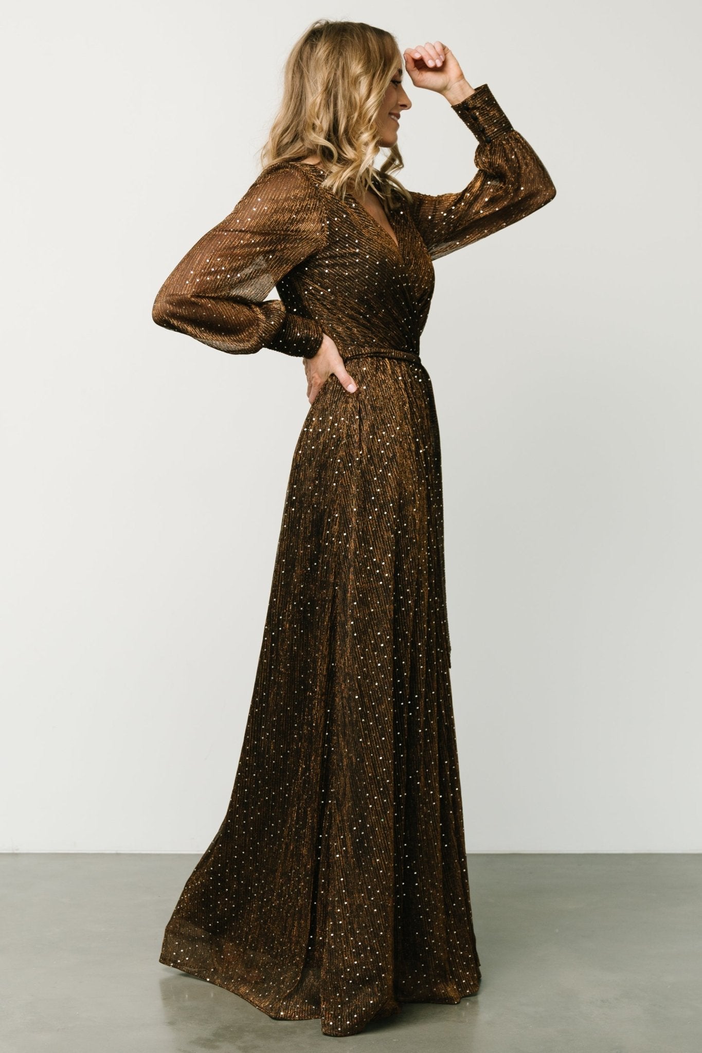 Back view showing keyhole and button closure at the neck and the subtle faux-wrap back shaping of the bronze sequin gown.