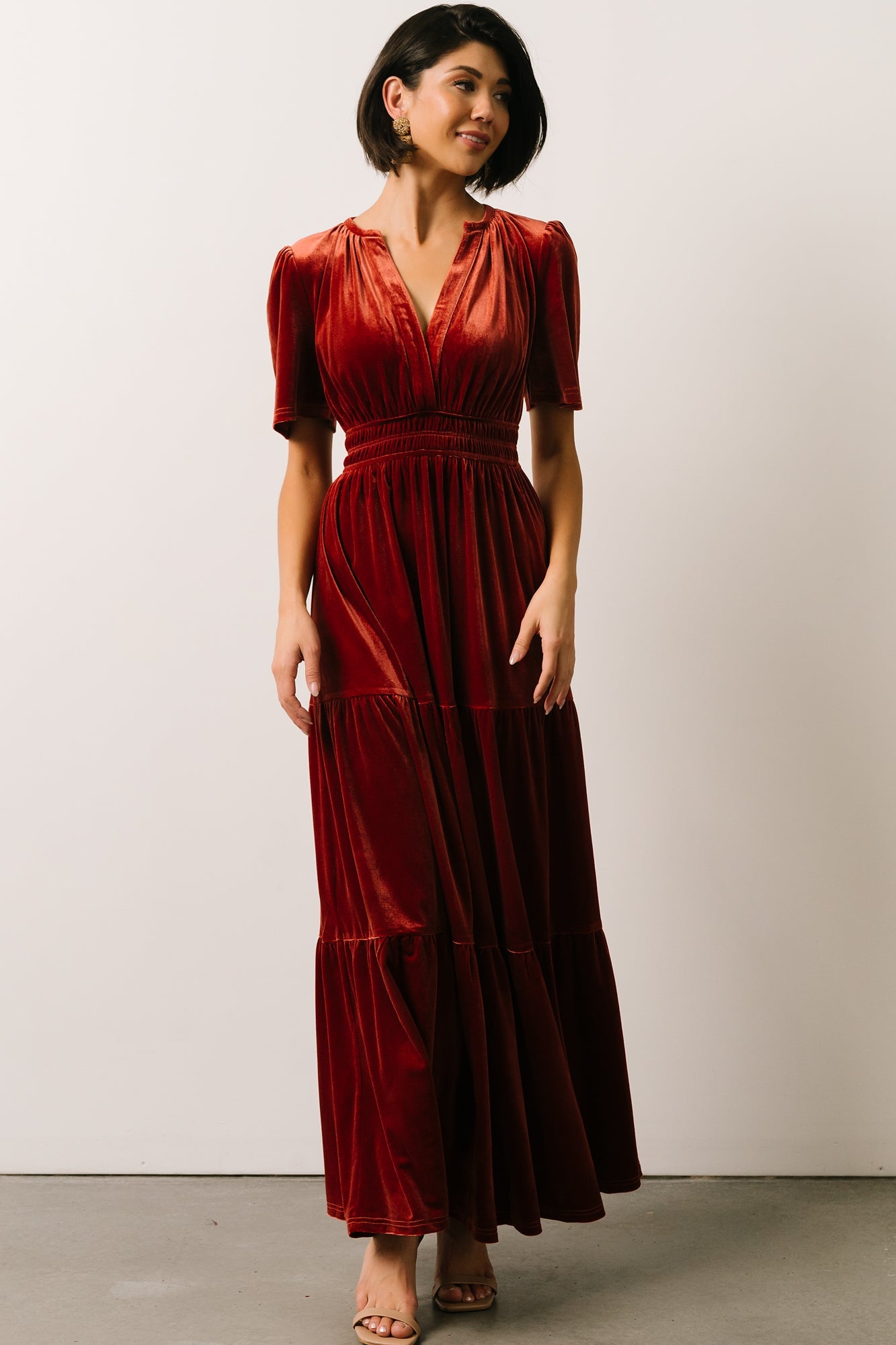 Close framing of the V-neckline and upper bodice of the terracotta velvet maxi, showing neckline depth and seam detail.