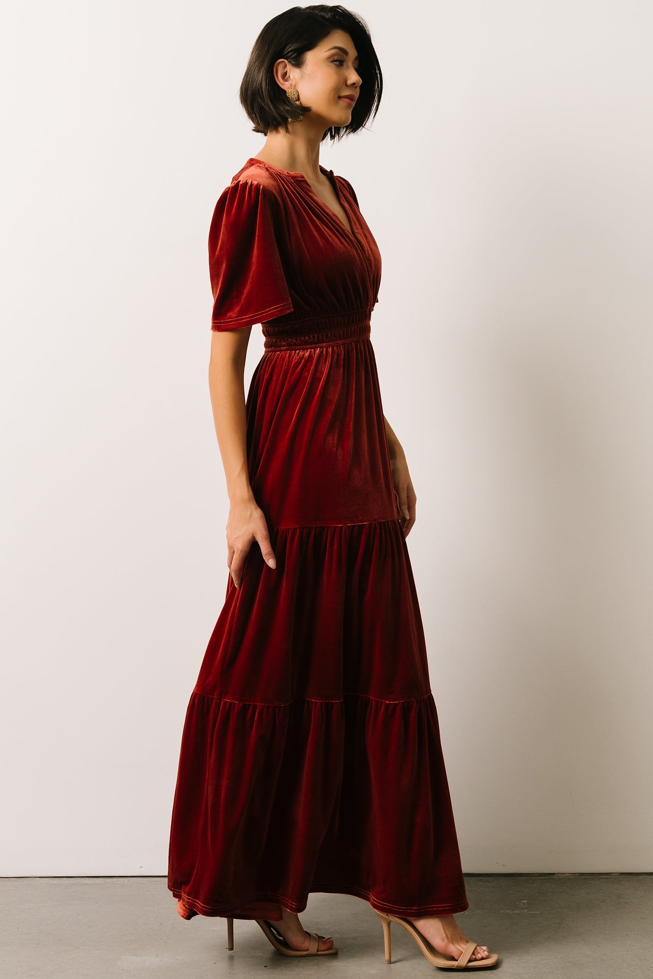 Full-length shot of Artemis terracotta velvet maxi dress showing tiered silhouette and graceful movement on the model.