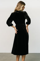 Lifestyle angle of the wrap midi in black velvet showing movement in the skirt and the flattering wrap closure at the waist.