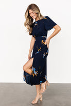 Full-length shot of the Eleanor Midi Dress in navy floral chiffon, styled with simple accessories to emphasize its elegant, wearable silhouette.