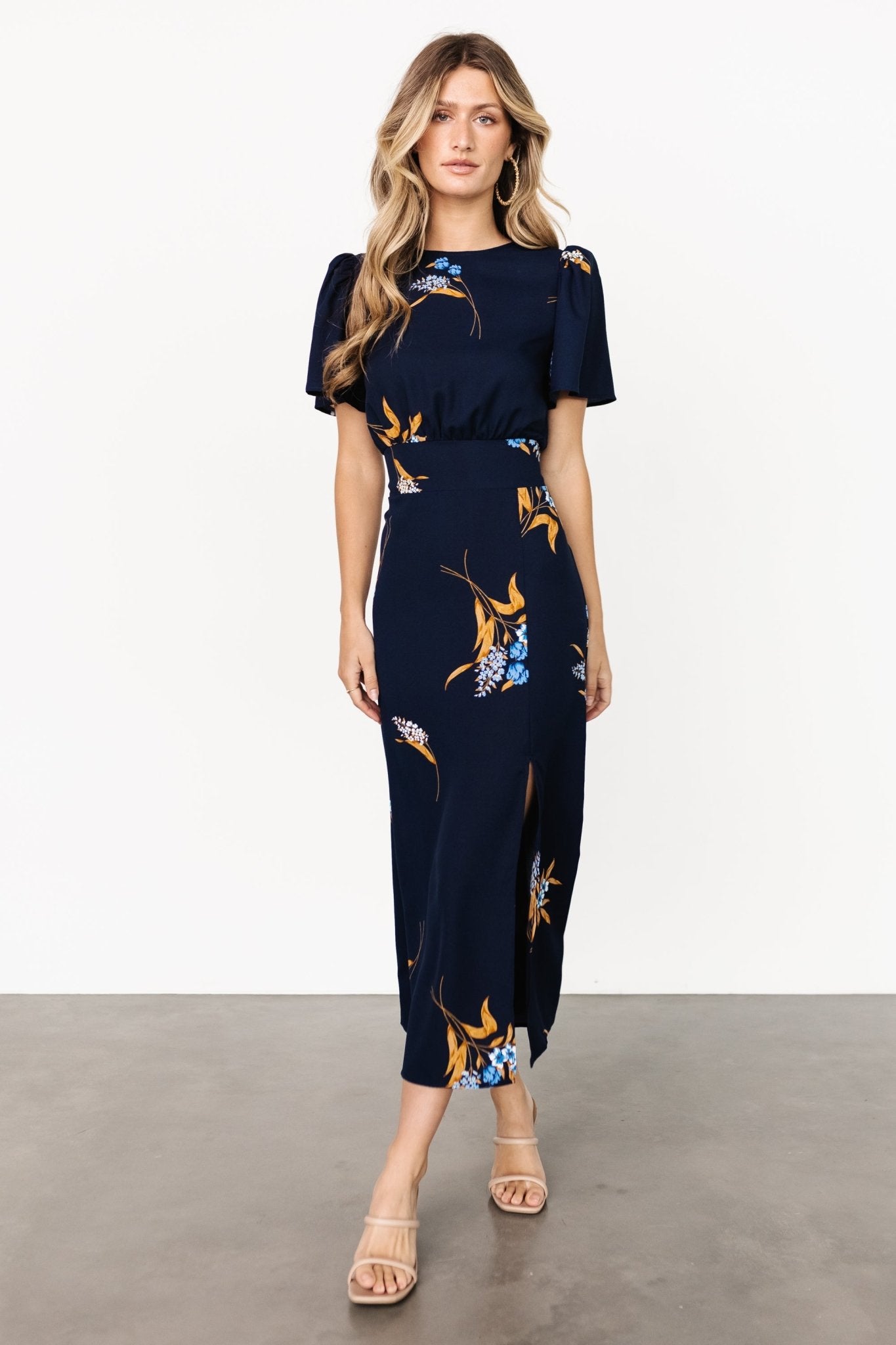 Front view of Eleanor Midi Dress in navy blue floral chiffon on a mannequin, short sleeves, banded waist, and left-side slit for movement and coverage.