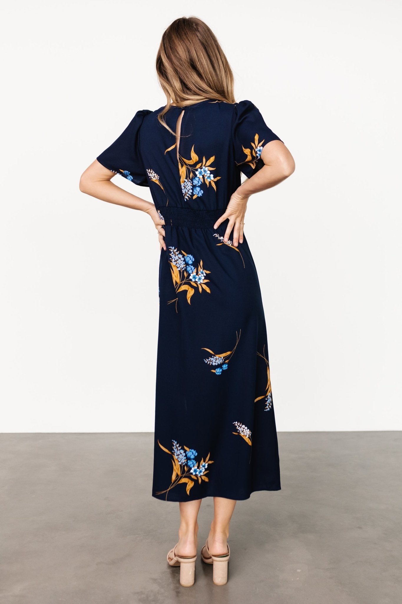 Model wearing Eleanor Midi Dress in navy floral, showing fit at the waist and natural movement of the chiffon skirt with a left-side slit.