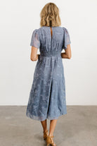 Model wearing blue smocked midi dress styled with neutral shoes, demonstrating the dress’s midi length and flow for daytime events.