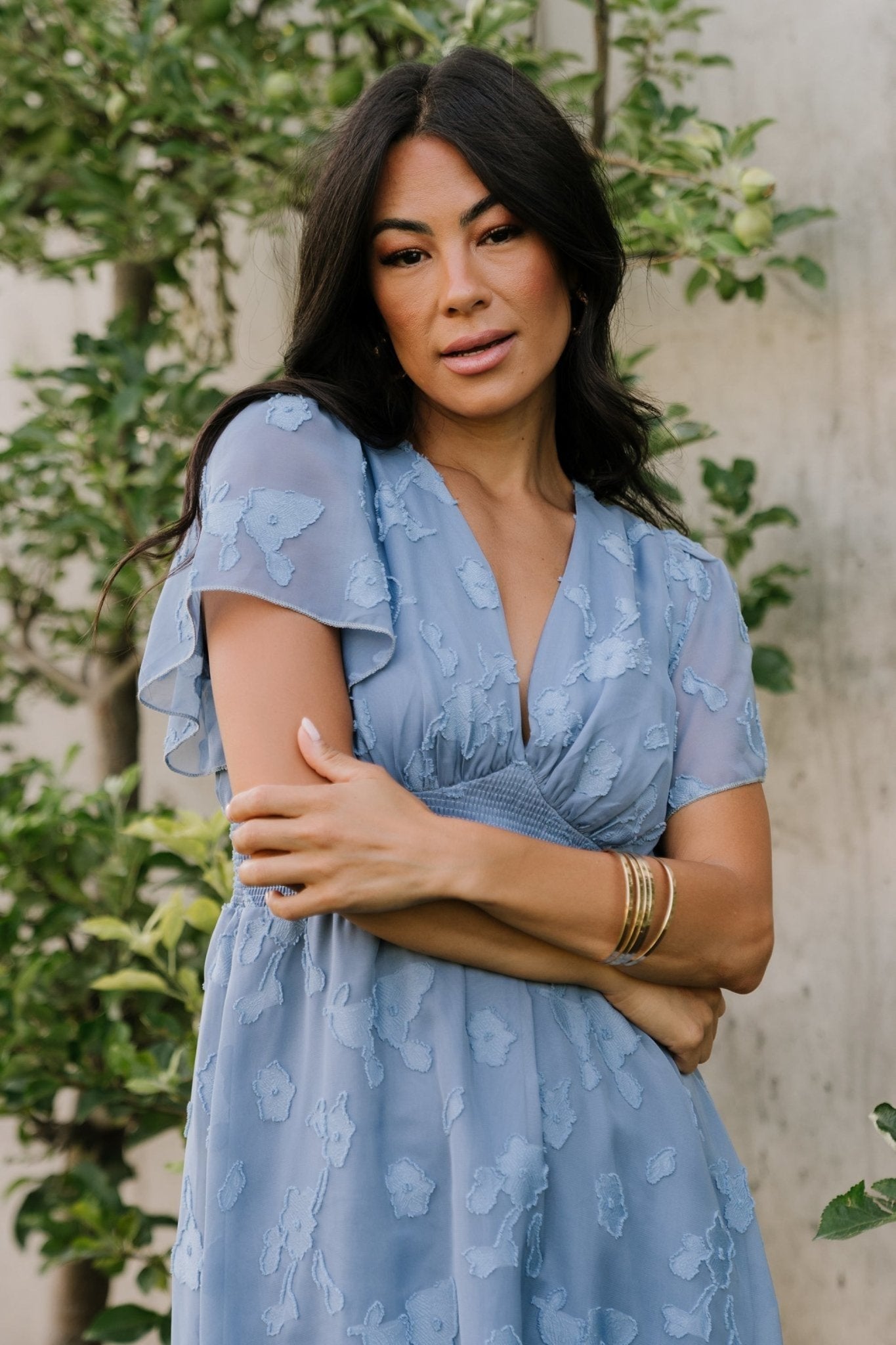 Close view of the V-neck and pleated bust detail on a blue floral chiffon midi dress, emphasizing thoughtful tailoring and shape.