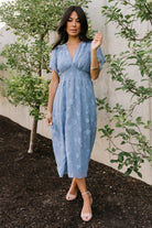 Close-up of smocked waist detail on a blue floral chiffon midi dress showing gathered elastic and delicate burnout texture.