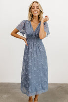 Back view of blue midi dress showing button-and-keyhole closure at the nape and the gathered smocked back for comfortable fit.