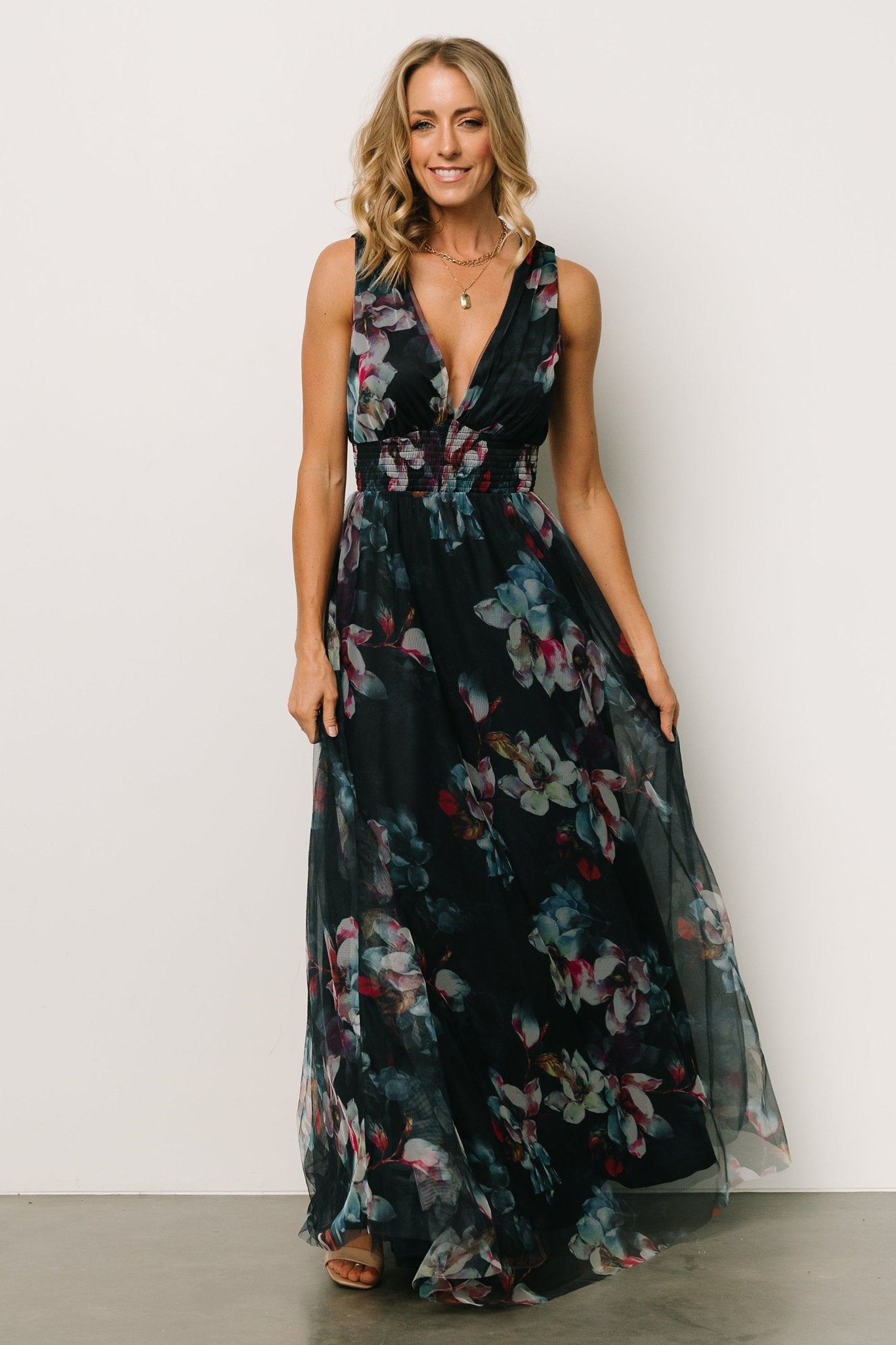 Styling view of the navy abstract floral maxi dress with emphasis on the smocked waist, flutter of the tulle skirt, and neckline detail.